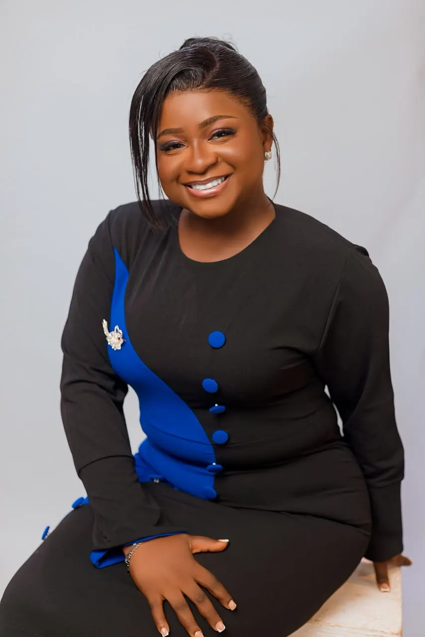 Grace Takyi seated, wearing a blue and black dress